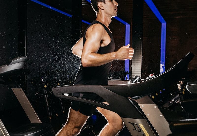 Topless Woman in Black Shorts and Brown Boots Sitting on Black Exercise Equipment